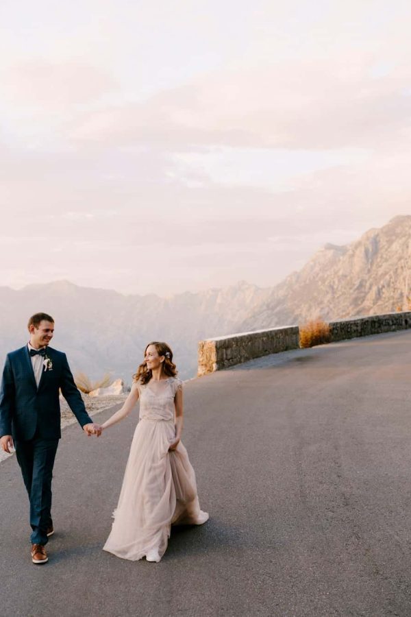bride-and-groom-are-walking-along-the-asphalt-road-against-the-background-of-mountains.jpg