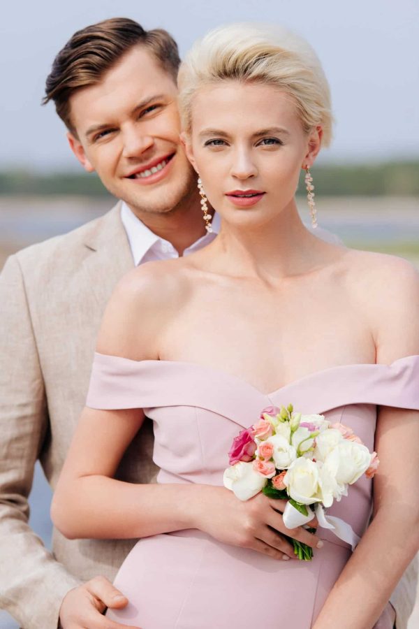 happy-just-married-couple-with-wedding-bouquet-looking-at-camera.jpg